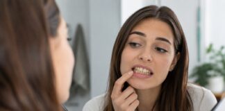 Στραβά δόντια: Γιατί δεν είναι μόνο αισθητικό πρόβλημα Γυναίκα παρατηρεί τα στραβά δόντια της στον καθρέφτη